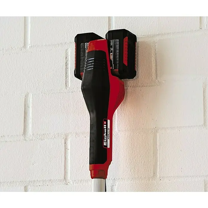 Einhell PXC 18V Desbrozadora de batería Agillo - 36 V, Iones de litio, Sin batería - Bordeadora inalámbrica Einhell Agillo con dos baterías montada en una pared de ladrillo blanco. Práctica para jardinería.