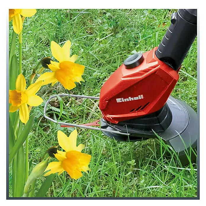 Einhell PXC 18V Recortabordes de batería GE-CT 18 Li-Solo - 18 V, Iones de litio, Sin batería - Primer plano de un cortabordes inalámbrico Einhell en acción, en medio de hierbas verdes y narcisos amarillos brillantes.