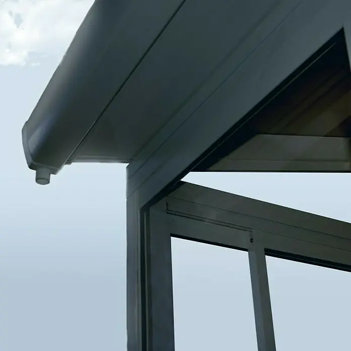 Palram – Canopia Porche acristalado San Remo - An x Pr x Al: 4,25 x 3 x 3,1 m, Gris antracita - Primer plano de un techo de patio moderno con canalón y perfiles de marco elegantes contra un cielo claro.