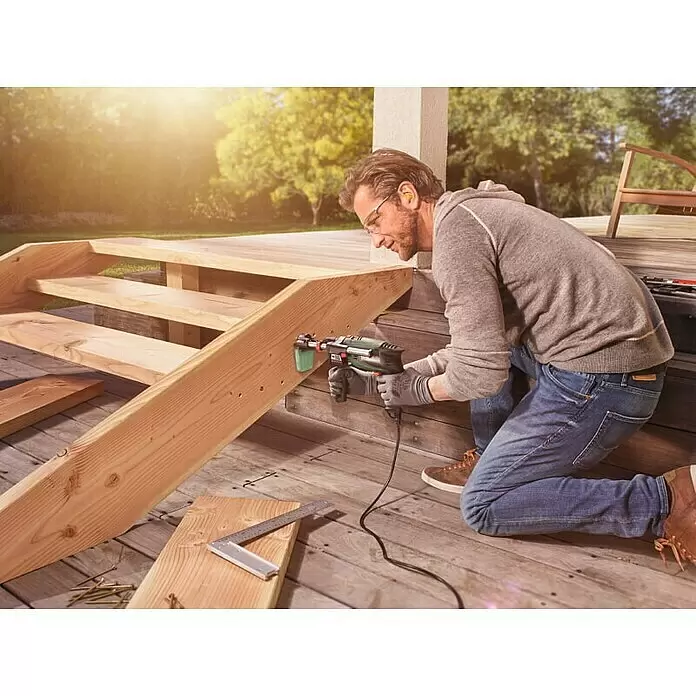 Bosch Taladro percutor UniversalImpact 700 + set X-Line - 700 W, Número de revoluciones de marcha en vacío 1ª marcha: 3.000 r.p.m., Número máx. de impactos: 45.000 /min - Hombre perfora escaleras de madera con herramienta rotativa Bosch negra y verde, con accesorio de polvo.