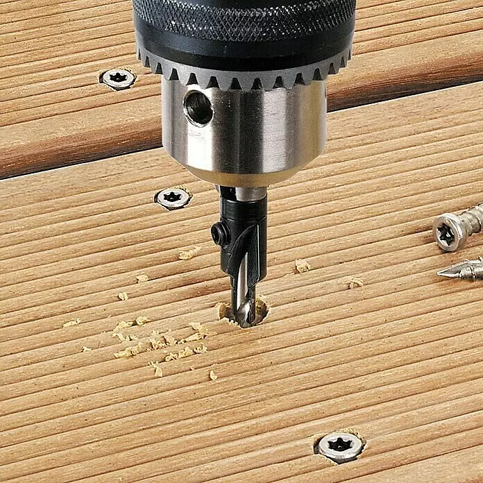 Wolfcraft Broca para madera con avellanador 4,5 - 11 mm - 1 ud., Diámetro de la broca: 150 mm - Una broca con avellanador negro perfora un orificio piloto en una tabla de cubierta de madera. Se ven virutas de madera.