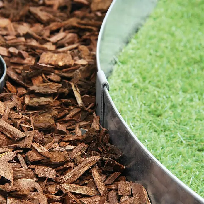 Bellissa Bodenanker RK19 - Passend für: Bellissa Rasenkanten mit 19,5 cm Höhe - Nahaufnahme einer flexiblen Metalleinfassung, die Holzspäne von einem Rasen trennt, ideal für Garten- und Landschaftsbauprojekte.