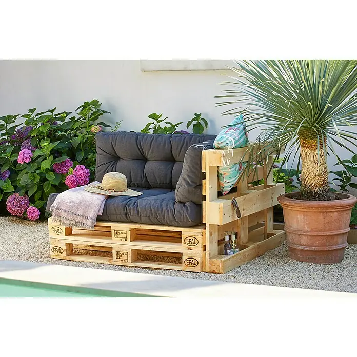 EuropaletteL x B x H: 120 x 80 x 14 cm, Unbehandelt - Gemütliche Outdoor-Lounge aus Paletten mit grauen Polstern, einem Hut und einer Decke, ideal zum Entspannen im Garten.