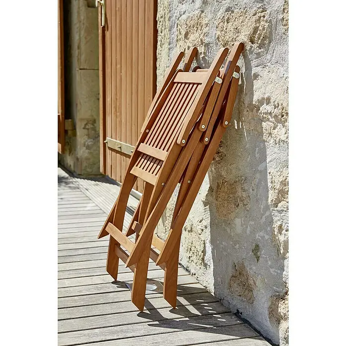 Sunfun Gartenmöbel-Set Diana - 5 -tlg., Akazie, Naturbraun - Zwei zusammengeklappte Holzstühle lehnen an einer Wand, die Stühle aus Holz sind braun und haben eine schöne Maserung.