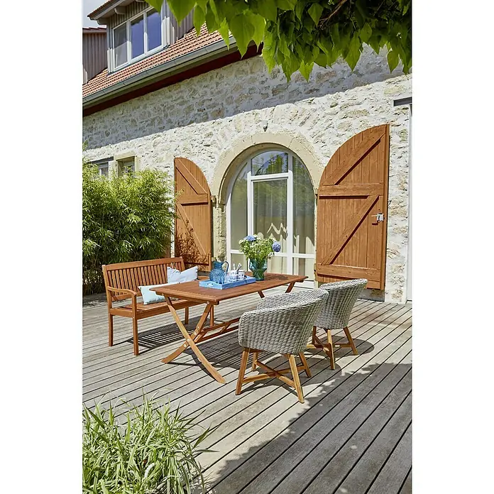 Sunfun Pauline Sillón de jardín Pauline - An x Pr x Al: 62 x 70 x 80 cm, Madera maciza, Bambus Grey, Antracita, Marrón natural - Foto luminosa al aire libre de un juego de jardín de madera que consta de una mesa, un banco y dos sillas en una terraza frente a una casa.
