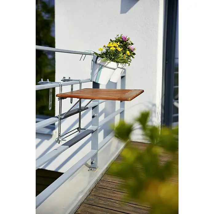 Sunfun Balkontisch - L x B x H: 40 x 60 x 1,5 cm, Akazie, Klappbar, Rechteckig, Natur - Balkon mit einem kleinen Holztisch, der an einem Geländer befestigt ist, und zwei weißen Pflanzgefäßen mit bunten Blumen.