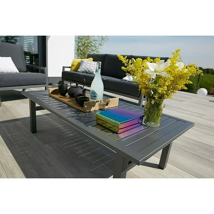 Sunfun Maja Conjunto de muebles - 4 pzs., Poliéster/Aluminio, Antracita - Una mesa de jardín gris con flores, bebidas y una caja encima, parte de un elegante conjunto de exterior para horas relajadas al aire libre.