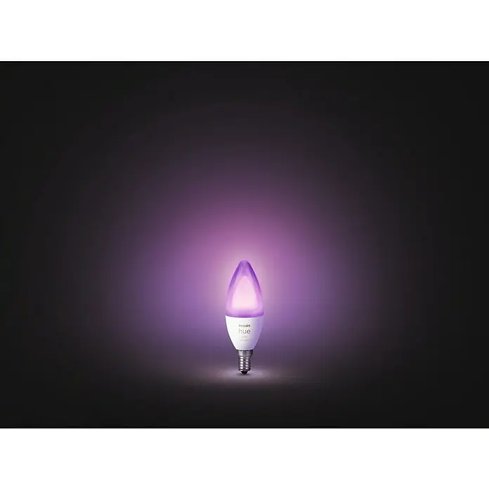 Philips Hue Bombilla LED inteligente Vela - E14, Intensidad regulable, RGBW, 470 lm, 5,3 W - Primer plano de una bombilla de vela Philips Hue, que brilla en un suave color púrpura, sobre un fondo oscuro.