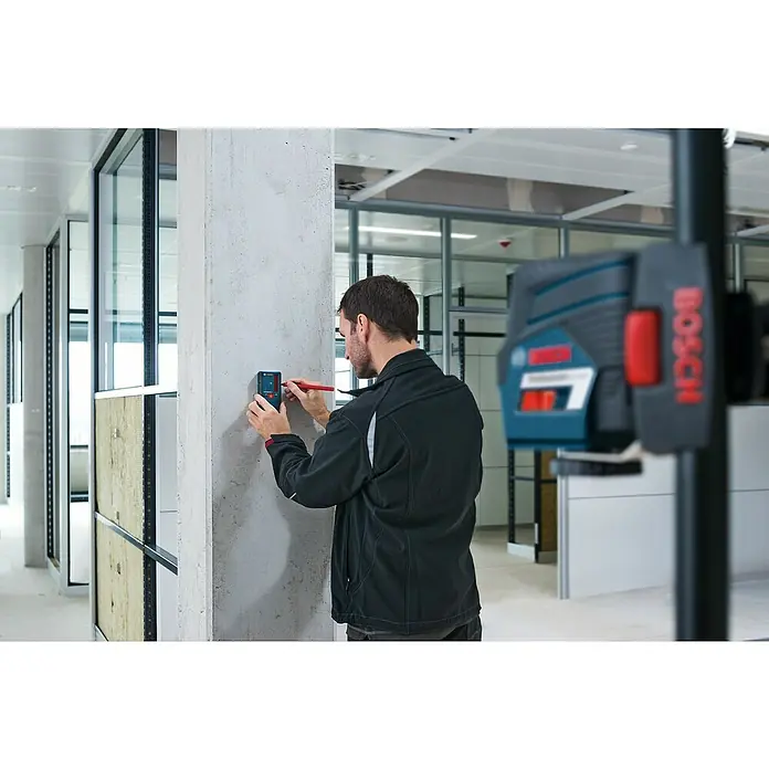Bosch Professional Laserempfänger LR 6 - Passend für: Bosch Professional Linienlaser GCL 2-50 C, GLL 3-80, GLL 3-80 C, Arbeitsbereich: 5 - 50 m - Ein Mann benutzt einen Bosch Laser-Entfernungsmesser, um Markierungen an einer Wand anzubringen. Das Gerät ist kompakt und benutzerfreundlich.