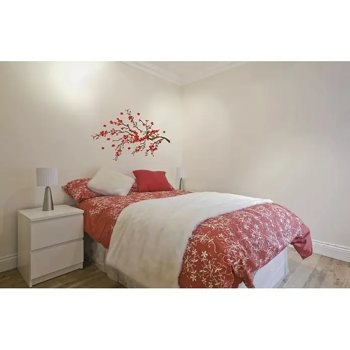 Vinilo de pared Red Ramage - Rojo, Plástico - Acogedora habitación con ropa de cama roja, almohadas blancas y una elegante calcomanía de pared sobre la cama.