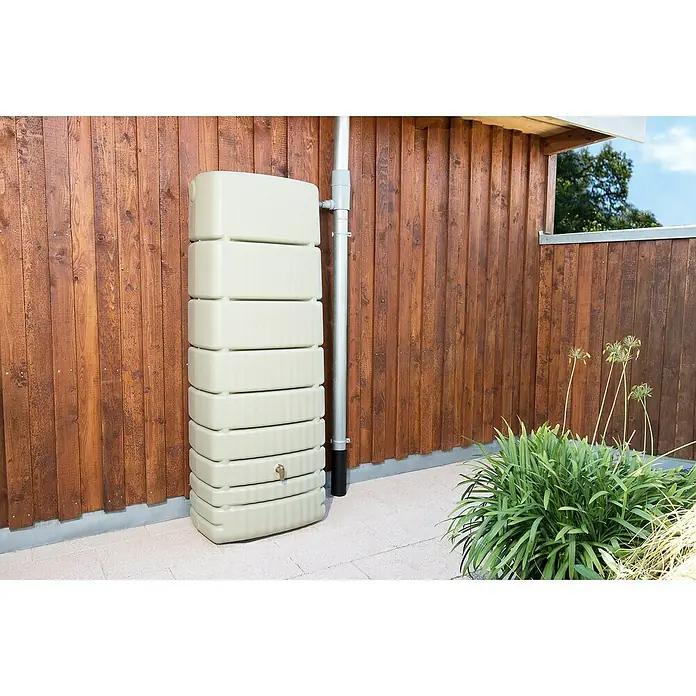 4rain Regenspeicher Slim - 650 l, Sandbeige - Regenwassertank aus Kunststoff mit Regenableiter vor einer Holzwand. Perfekt zur Gartenbewässerung und Wassereinsparung im Haushalt.