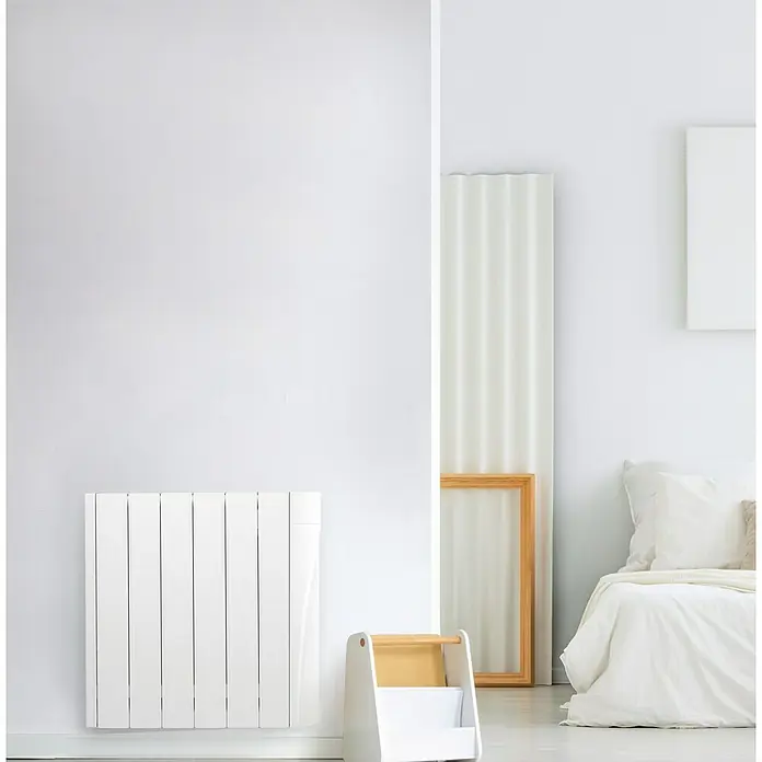 Voltomat HEATING Emisor térmico VOLCW - 1.000 W, Blanco, 9,8 x 58,5 x 57,5 cm, Cerámico - Un radiador blanco montado en una pared blanca en una habitación luminosa, presentando una estética minimalista y moderna.