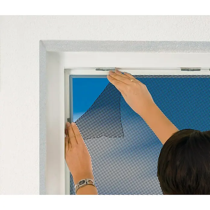 Easy Life Insektenschutzvorhang Premium - B x H: 100 x 220 cm, Anthrazit, Montage Insektengitter: Ankletten - Das Bild zeigt eine Person, die ein Insektenschutzgitter an einem Fenster anbringt, um Insekten fernzuhalten.