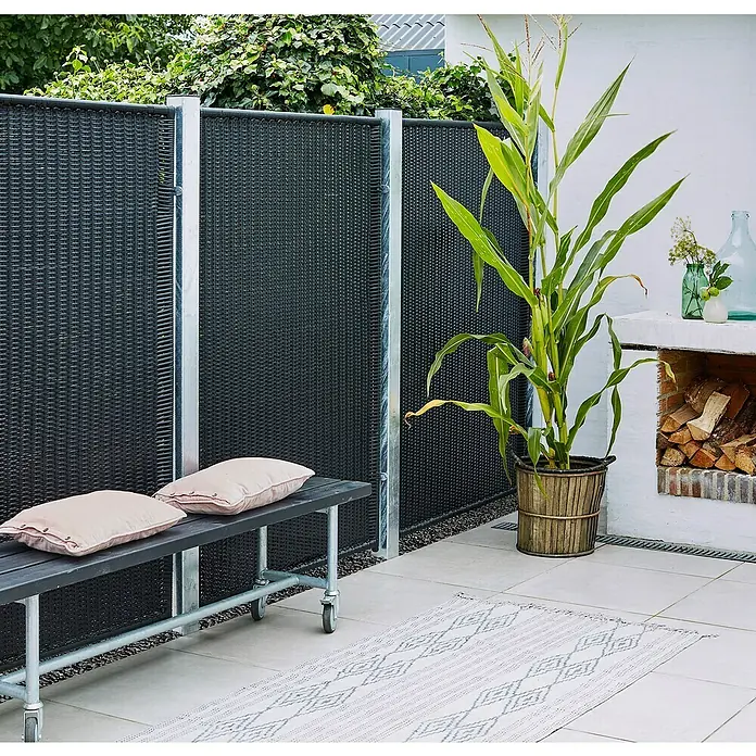 Plus Sichtschutzelement - 115 x 170 cm, Kunststoff, Schwarz - Eine Szene im Freien mit einem stilvollen, schwarzen Sichtschutzzaun, einer Bank mit Kissen und einer Dekorationsecke mit Pflanzen.