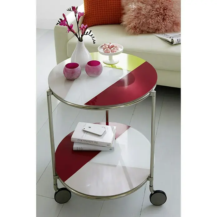 D-c-fix Klebefolie Uni Lack - 200 x 67,5 cm, Magnolie, Selbstklebend - Dekorativer runder Beistelltisch mit zwei Ebenen und Rollen, verziert mit roten und grünen Farbakzenten.