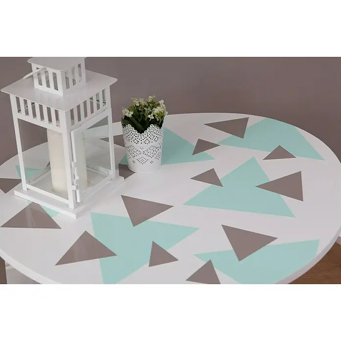 D-c-fix Klebefolie Uni Lack - 200 x 45 cm, Mint, Selbstklebend - Nahaufnahme eines runden Tisches mit geometrischem Dreiecksmuster, einer weißen Laterne und einem Topf mit Kunstblumen.