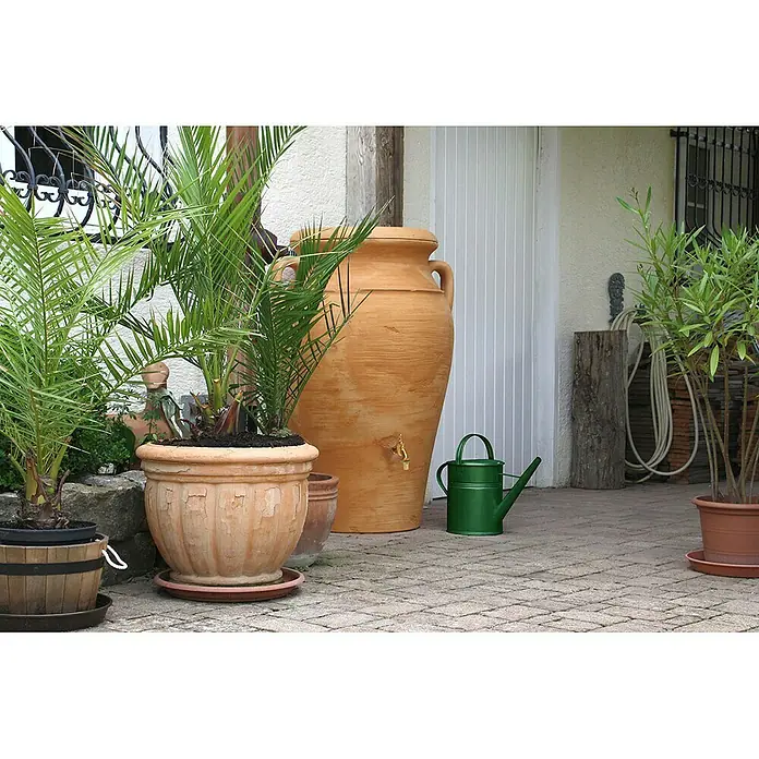 Arves Regenspeicher Amphore Helena - 300 l, Terra/Antik - Dekorative Gartenszene mit Pflanzen, einem großen Krug und einer grünen Gießkanne auf einem gepflasterten Bereich.