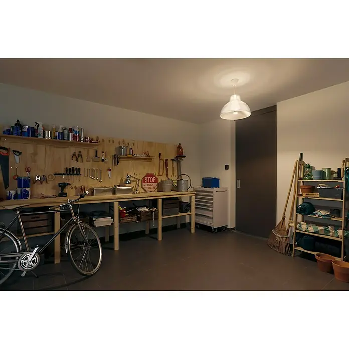 Philips Hue Smart-LED-Lampe White - E27, Dimmbar, Warmweiß, 1.600 lm, 15,5 W, 1 Stk. - Werkstatt-Interieur mit Werkzeugen, Fahrrad und Regalen unter einer hängenden Lampe, die den Raum erhellt. Vielseitige Aufbewahrungslösung.