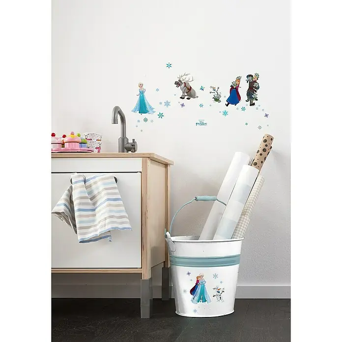 Komar Dekosticker Frozen - B x H: 14 x 33 cm, Bunt - Kinderzimmer mit "Die Eiskönigin"-Wandstickern und einem Dekoeimer mit "Die Eiskönigin"-Motiv, der mit Geschenkpapierrollen gefüllt ist.