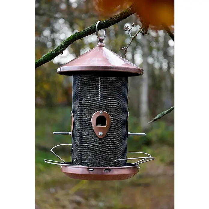 Dobar Futterspender - Material: Metall, Mit Silo - Nahaufnahme eines Kupfer-Vogelfutterhäuschens, das an einem Ast hängt, gefüllt mit Samen und bereit für gefiederte Besucher.