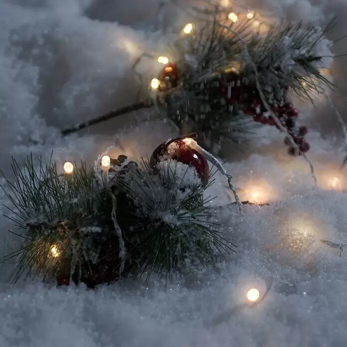 Konstsmide LED-Lichtervorhang Eisregen - Außen, 3,5 m, Warmweiß, 80 Stk., Batteriebetrieben - Festliche Weihnachtsdeko: verschneite Tannenzweige mit roten Beeren und einer Kugel, beleuchtet von warmen Lichterketten im Schnee.