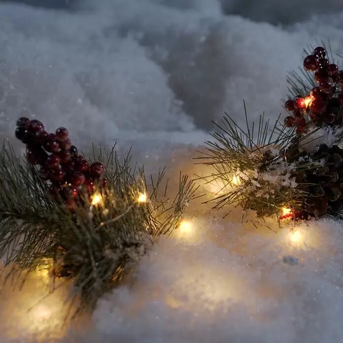 Konstsmide LED-Lichterkette Micro LED - Innen, Lichtfarbe: Bernstein, Anzahl Leuchtmittel: 20 Stk., Batteriebetrieben, 1,9 m, Silber - Festliche Tannenzweige mit roten Beeren und warmen Lichtern im Schnee.
