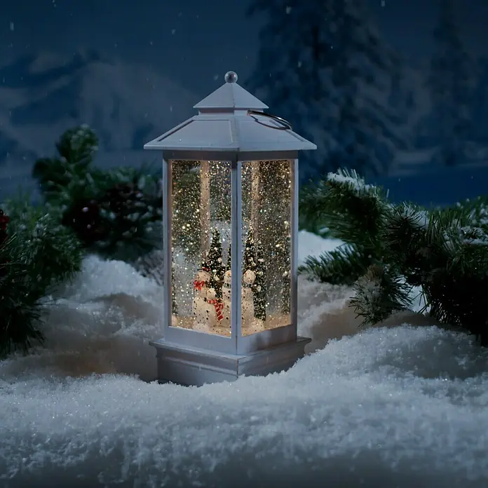 Konstsmide LED-Schneelaterne Schneemänner - Innen, Weiß, 10,5 x 10,5 x 27,5 cm, Batteriebetrieben - Winterliche Szene mit einer weißen Laterne, die eine Schneekugel mit Schneemann und Tannenbäumen enthält, umgeben von Schnee.