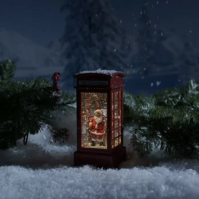 Konstsmide LED-Schneelaterne - Innen, Rot, 9,5 x 9,5 x 20 cm, Laterne, Batteriebetrieben - Rote Telefonzellen-Schneekugel mit Weihnachtsmann im Inneren, beleuchtet und umgeben von Schnee und Tannenzweigen in winterlicher Umgebung.