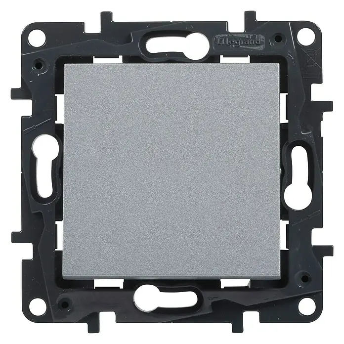 Legrand Niloé Step Pulsador para estancias con humedad - Aluminio, Montaje en la pared - Primer plano de un interruptor de luz gris Legrand con un borde oscuro y orificios de montaje.