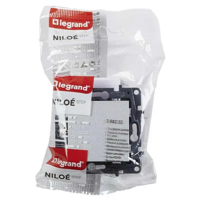 Legrand Niloé Step Pulsador para estancias con humedad - Aluminio, Montaje en la pared - Primer plano de un interruptor Legrand Niloe Step en un embalaje transparente, mostrando detalles del producto.
