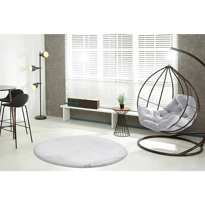 Fellteppich Happy - Silber, Durchmesser: 160 cm, 100 % Polyester (Flor) - Ein stilvolles Interieur mit einem weichen, runden Teppich, einem hängenden Sessel und modernen Möbeln, das eine gemütliche und einladende Atmosphäre schafft.
