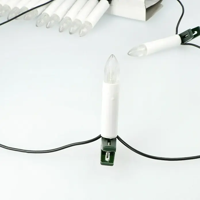 Tween Light Velas de Navidad LED - 14,55 m, Blanco, Color de luz: Blanco cálido, 30 ud., IP20 - Primer plano de una vela LED para ventana con cuerpo blanco y clip verde, parte de una cadena de luces sobre un fondo blanco.
