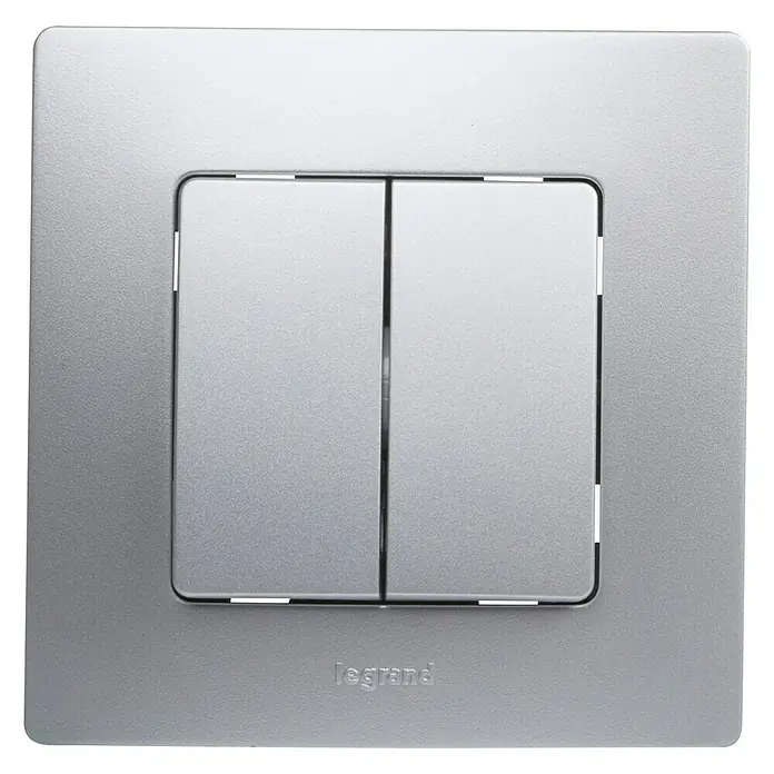 Conmutador doble Niloé Monoblock - Plateado, Montaje en la pared - Primer plano de un interruptor de luz doble Legrand con dos interruptores en una placa frontal cuadrada plateada. Ideal para interiores modernos.