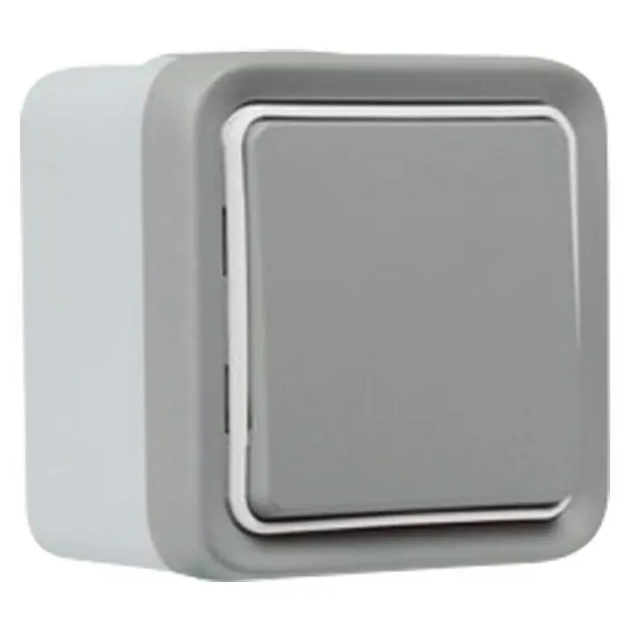 Legrand Plexo Pulsador para estancias con humedad inalámbrico - Gris, Montaje en la pared, IP55 - Primer plano de un interruptor de luz gris con adornos plateados sobre un fondo negro. Destaca una forma cuadrada y una estética moderna.