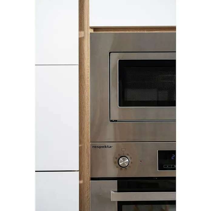 Respekta Premium Composición de cocina Lorena - Ancho: 270 cm, Blanco, Brillo intenso, Decoración encimera: Efecto madera, Con electrodomésticos - Primer plano de un electrodoméstico empotrado Respekta con microondas y horno en una cocina moderna con armarios blancos y detalles de madera.