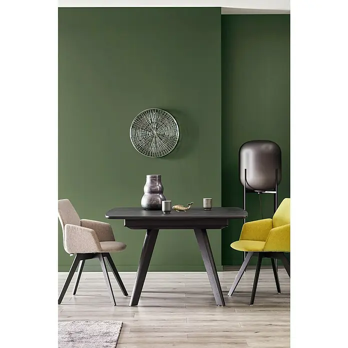 SCHÖNER WOHNEN-Farbe Wandfarbe Trendfarbe - Jungle, Matt, 2,5 l, Konservierungsmittelfrei - Eine elegante Essgruppe mit einem dunklen Esstisch, hellen und gelben Armlehnstühlen vor einer olivgrünen Wand.