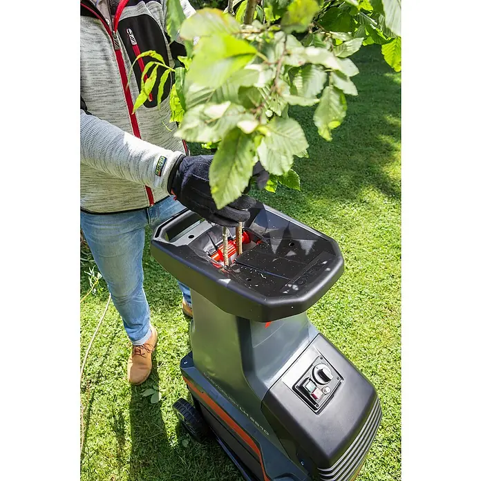 AL-KO Easy Crush Elektro-Walzenhäcksler LH 2810 - Max. Aststärke: 4,2 cm, 2.800 W - Ein Mann benutzt einen AL-KO Easy Crush LH 2810 Gartenhäcksler, um Äste zu zerkleinern. Der Häcksler steht auf einer grünen Rasenfläche.