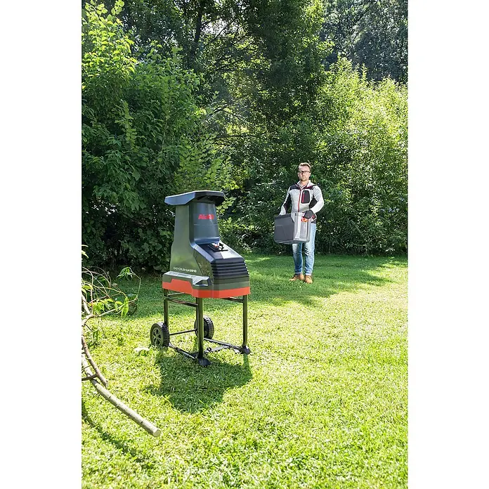 AL-KO Easy Crush Elektro-Walzenhäcksler LH 2810 - Max. Aststärke: 4,2 cm, 2.800 W - Der AL-KO Easy Crush LH 2810 Häcksler steht auf dem Rasen, während ein Mann den Auffangbehälter hält.