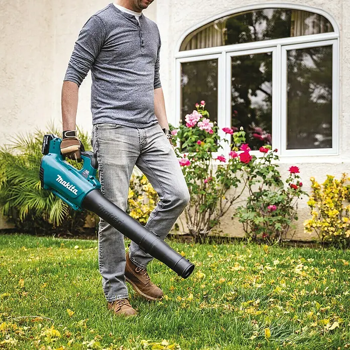 Makita LXT 18V Akku-Gebläse DUB184Z - 18 V, Ohne Akku, Blasgeschwindigkeit: 52,1 m/s - Ein Mann im Garten hält einen Makita Akku-Laubbläser. Ideal zum Entfernen von Blättern.