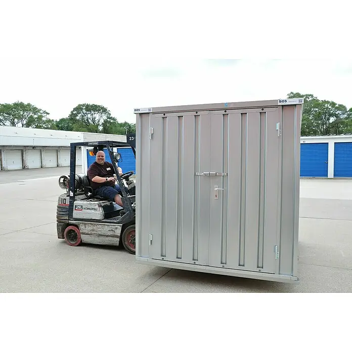 BOS Best of Steel Schnellbaucontainer SC3000-2x2-SZS - 2,1 x 2,1 x 2,1 m, Stahl, Doppeltür - Ein Mann auf einem Gabelstapler transportiert eine robuste Lagerbox von BOS. Ideal für sichere Aufbewahrungslösungen im Freien.