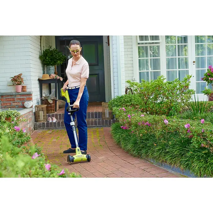 Ryobi ONE+ Limpiador de juntas de batería RY18PCA-0 - 18 V, Iones de litio, Sin batería - Una mujer usa un bordeador Ryobi en su jardín para recortar el césped a lo largo de los bordes.
