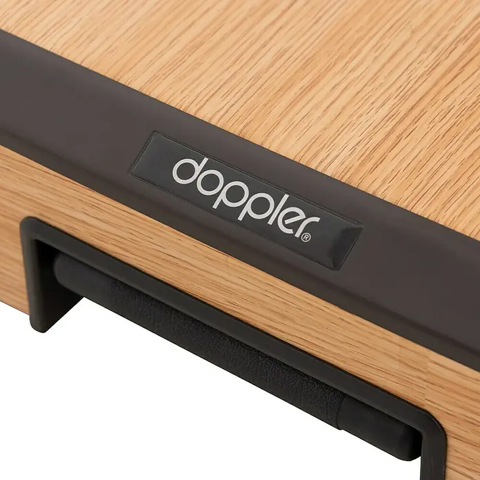 Doppler Schirmständer Trolley - 56 x 56 x 16 cm, Holz, Passend für: Schirme bis Ø 300 cm - Nahaufnahme eines Doppler-Produkts mit Holzstruktur und dem Doppler-Logo auf einem schwarzen Etikett. Griffdetail in der unteren Ecke.