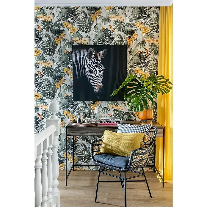 Papel pintado Vegetal flor - Amarillo/verde, 10 x 0,53 m - Área de escritorio decorativa con papel tapiz estampado, obra de arte de cebra y una elegante silla de ratán con cojín amarillo.