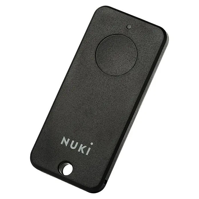Nuki Fernbedienung FOB - L x B x H: 6 x 55 x 24 mm - Nahaufnahme des Nuki-Fobs, eines kleinen, schwarzen, rechteckigen Geräts mit einer runden Taste und dem Nuki-Logo.