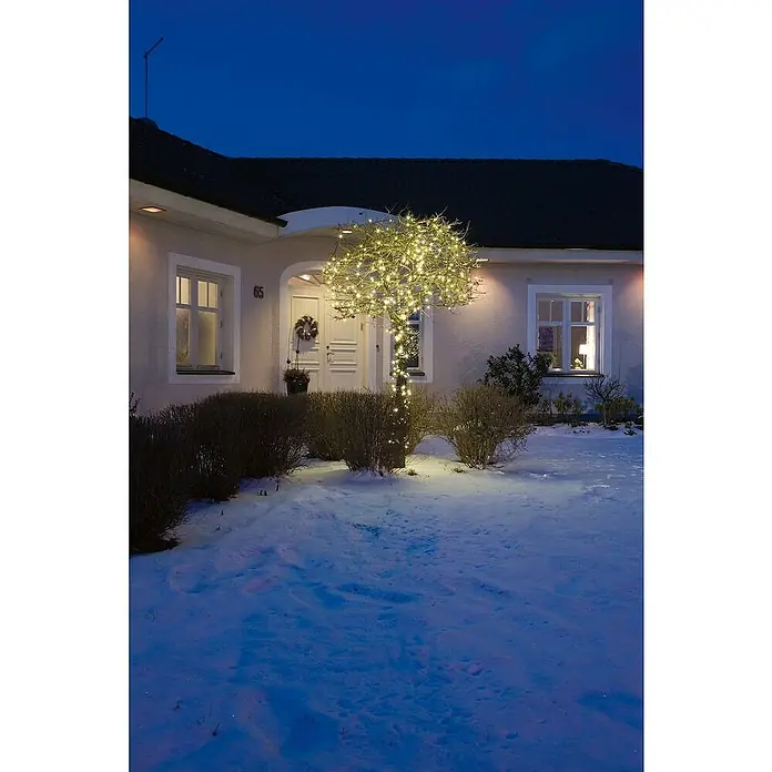 Konstsmide LED-Lichterkette - Außen, Lichtfarbe: Bernstein, Anzahl Leuchtmittel: 500 Stk., Netzbetrieben, 34,93 m - Ein Haus mit einer beleuchteten Birke im Schnee. Die Lichter erhellen den Garten und schaffen eine winterliche Atmosphäre am Haus.