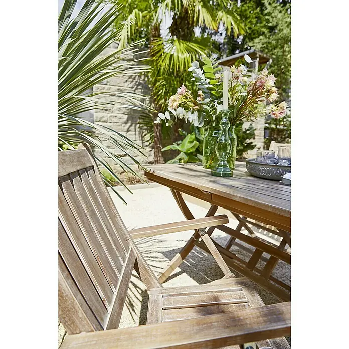 Sunfun Gartenmöbel-Set - 5 -tlg., Akazie, White washed - Nahaufnahme eines Holztisches und Stuhls im Freien, dekoriert mit Blumen und Kerzen für eine entspannte Atmosphäre.