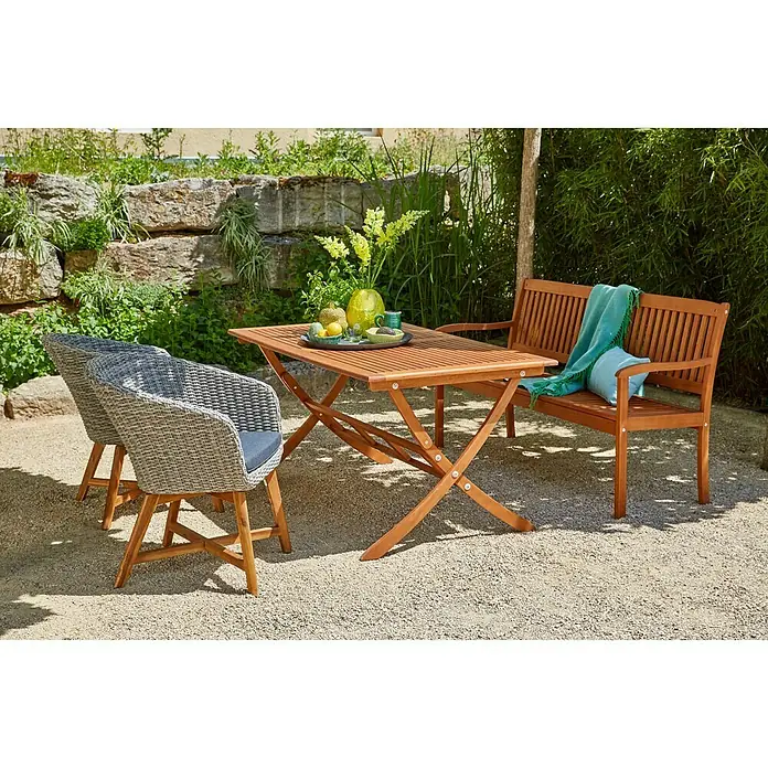 Sunfun Pauline Sillón de jardín Pauline - An x Pr x Al: 62 x 70 x 80 cm, Madera maciza, Bambus Grey, Antracita, Marrón natural - Un conjunto de muebles de jardín con mesa de madera, dos sillas de mimbre y un banco de madera con manta y cojín turquesa sobre grava.
