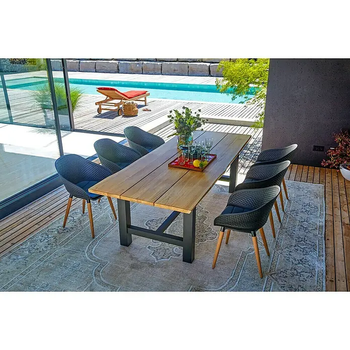 Sunfun Gartentisch - L x B x H: 240 x 100 x 75 cm, Aluminium. Teak, Rechteckig, Natur/Anthrazit - Ein einladender Außenbereich mit einem Esstisch aus Holz und stilvollen schwarzen Stühlen auf einem gemusterten Teppich.
