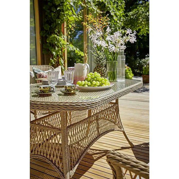 Sunfun Mesa de jardín Sophie - L x An x Al: 140 x 80 x 72 cm, Aluminio, Beige - Primer plano de una mesa de ratán exterior con tazas de té doradas, vasos, fruta y flores para una comida al aire libre.