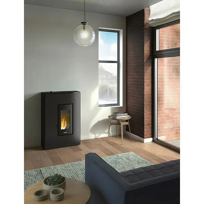FreePoint Pelletofen Atrium - 5,2 kW, Raumheizvermögen: 67 m³ - 125 m³, 0,57 kg/h - 1,31 kg/h, Anthrazit - Ein moderner, schwarzer Freeport-Kaminofen steht im Wohnzimmer und sorgt für Wärme und Atmosphäre mit einem Blick auf das gemütliche Kaminfeuer.